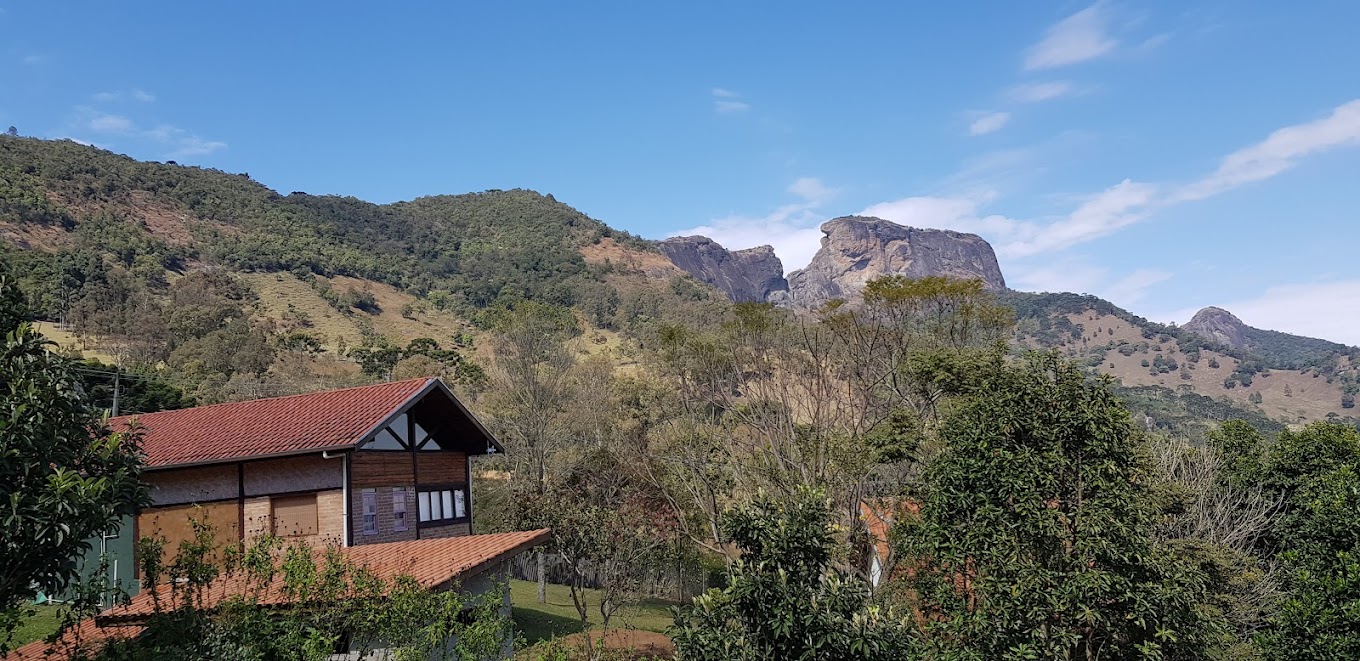 Cabana de madeira com redes e montanhas ao fundo ao entardecer